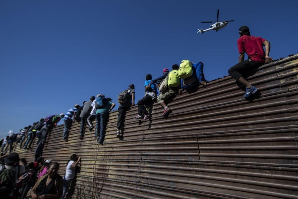 Immigrants climbing southern border wall
